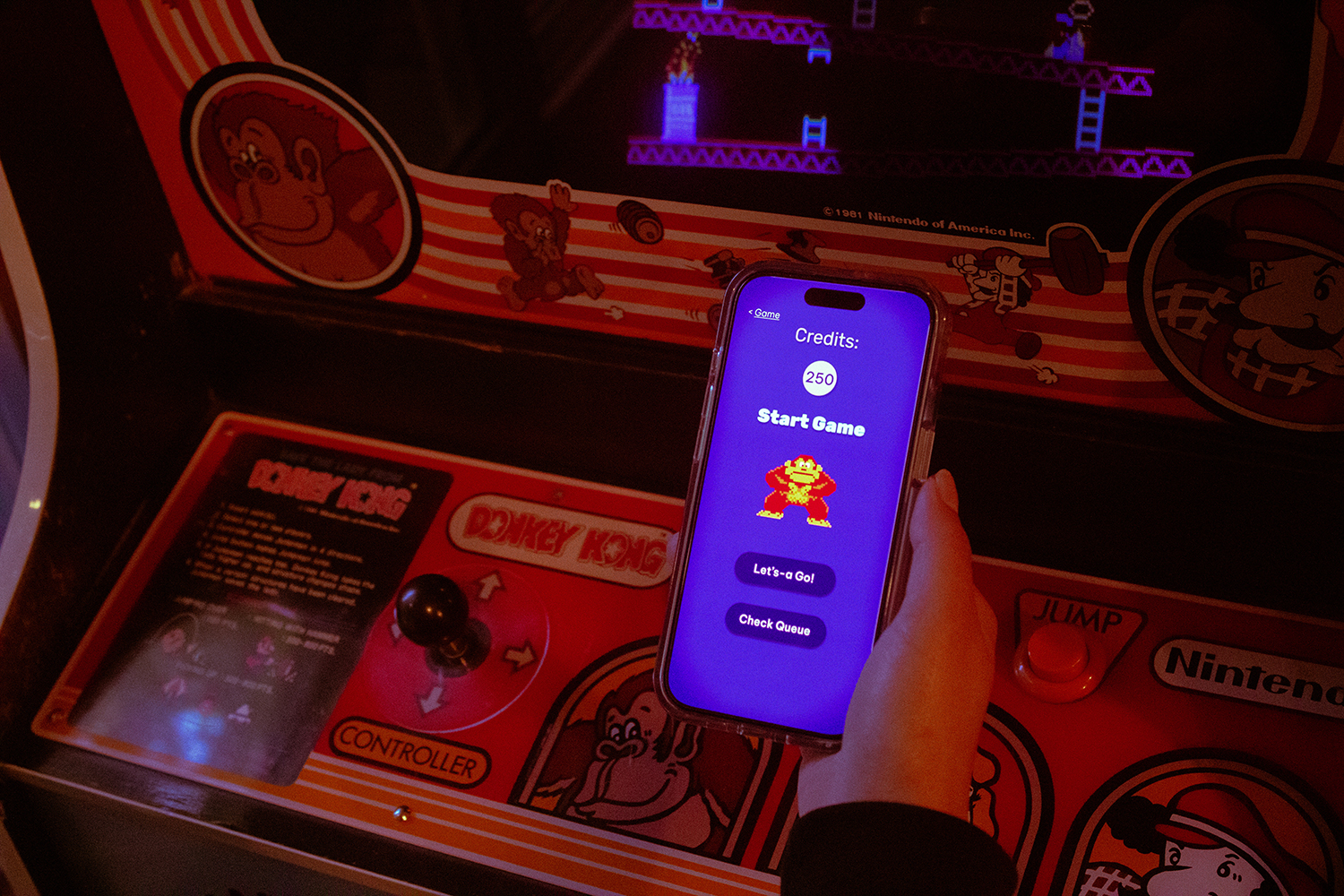 photograph of an iPhone with the prototype held in front of a Donkey Kong arcade machine
